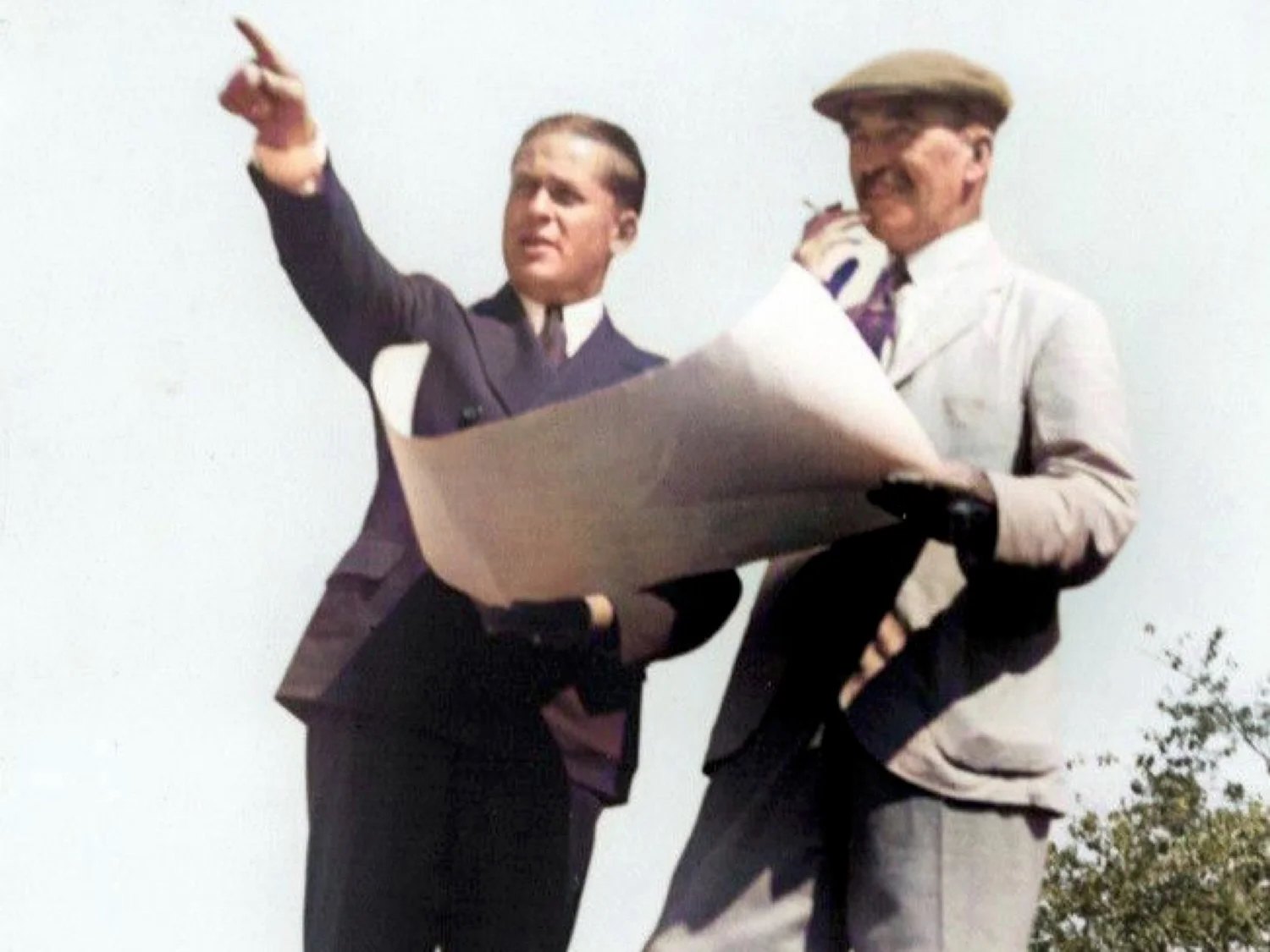 Bobby Jones and Alister MacKenzie on the Augusta site, holding a routing plan while Jones points across the ground.